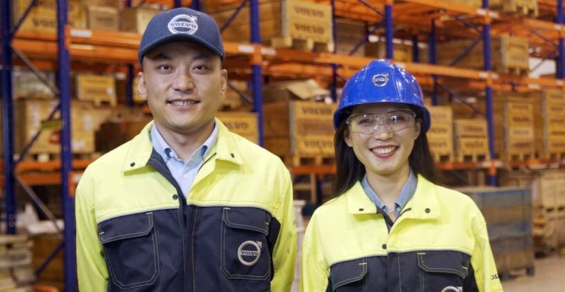 Man and woman smiling, standing in warehouse 