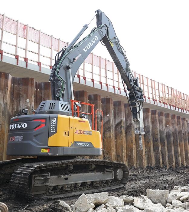 A closeup of a Volvo ECR355 mid-size short-swing crawler excavator with a breaker attachment for demolition.