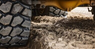 Nærbillede af hjul og aksler på en rammestyret Volvo dumper, som kører selvsikkert gennem dybt mudder