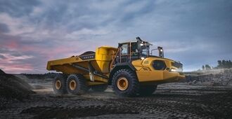 Un tombereau automoteur articulé Volvo A35 avec une pleine charge de matériaux  à la tombée du jour dans une carrière.