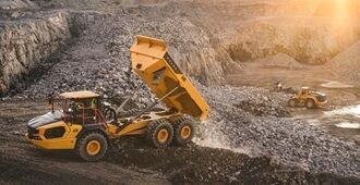 A Volvo A40 articulated hauler empties a load of material in a quarry environment.