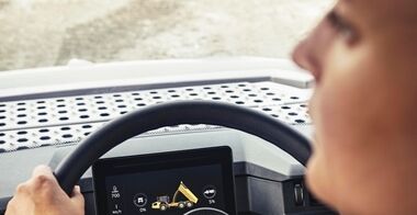Close up of the operator’s face and hands on the steering wheel of a Volvo Articulated Hauler with Haul Assist functionality on the integrated Co-Pilot
