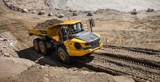 A Volvo Articulated Hauler A40 is climbing a steep gradient in a quarry environment carrying a full load of material.