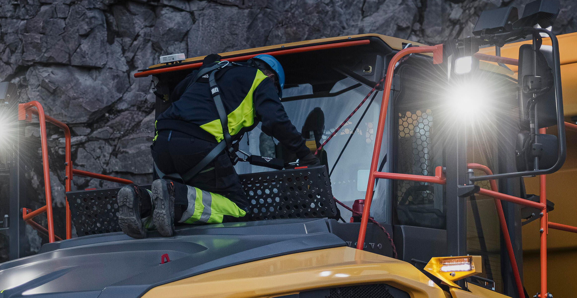 A Volvo technician is safely harnessed to the harness anchor points on a Volvo Articulated Hauler.
