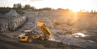 A Volvo A40 articulated hauler empties a load of material in a quarry environment.