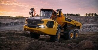 En rammestyret Volvo A45 dumper kører hen over vanskeligt terræn i et stenbrud, mens solen går ned.