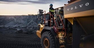 En operatør på platform til en rammestyret A45 Volvo dumper, som kigger ud over et stenbrud.