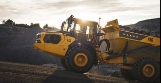 Volvo A50 full suspension articulated hauler driving uphill in a quarry environment