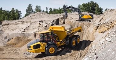 Volvo A50 full suspension articulated hauler being loaded by a Volvo EC750 excavator in a sandy quarry environment