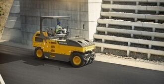 Side view of the Volvo PT220 tyre roller passing under a bridge on an highway