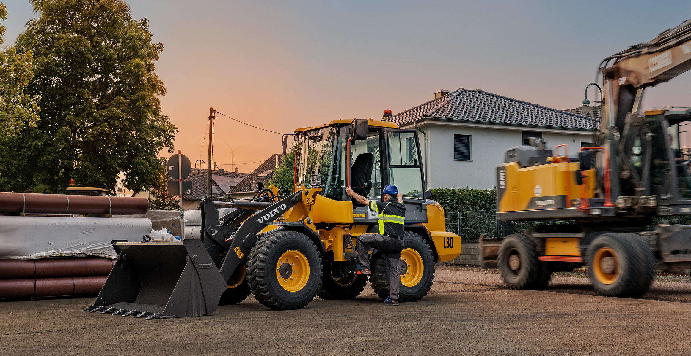 Volvo L30 Compact Wheel Loader operating in a construction yard with another loader nearby.