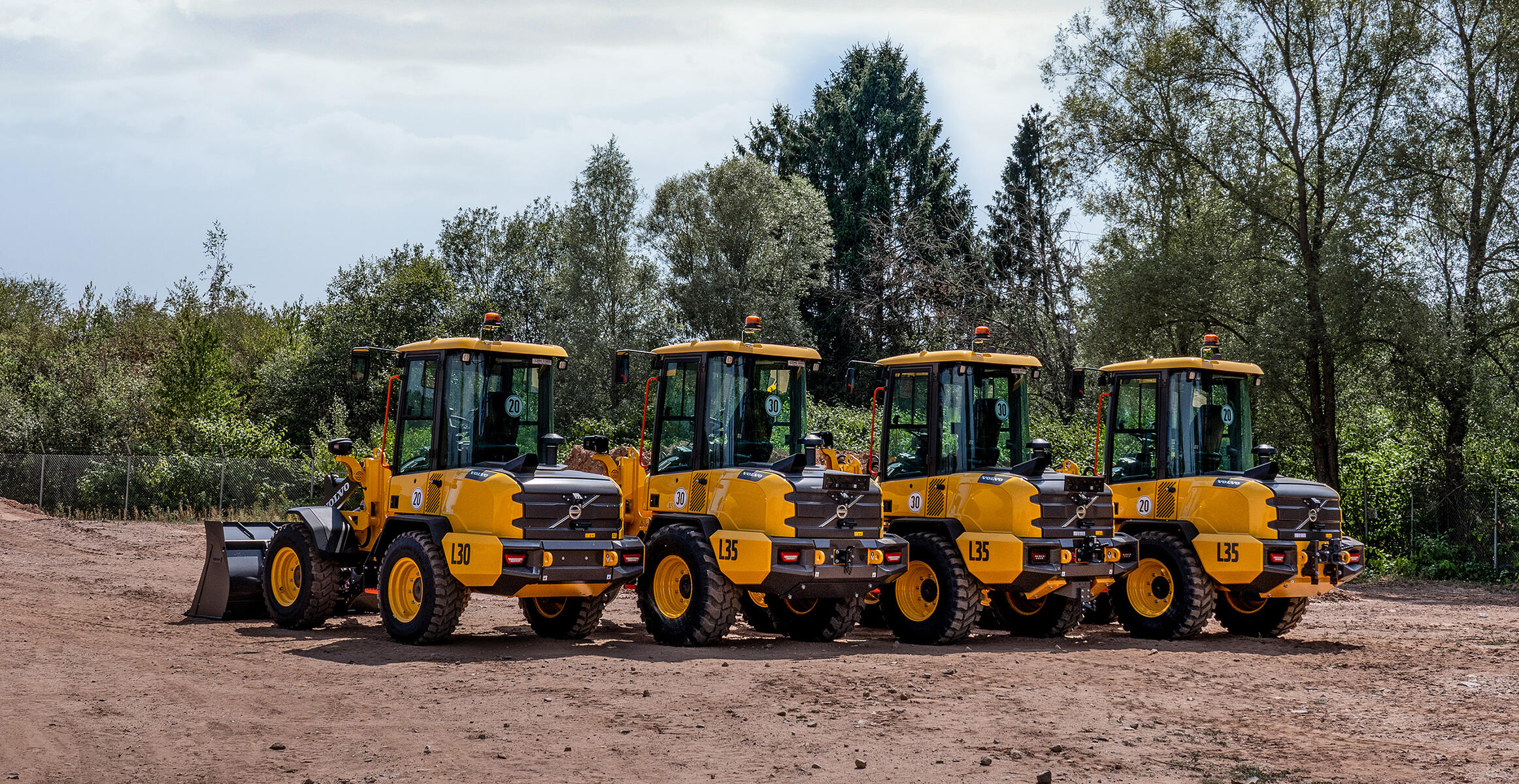 Four Volvo L30 L35 Compact Wheel Loaders lined up on a jobsite.