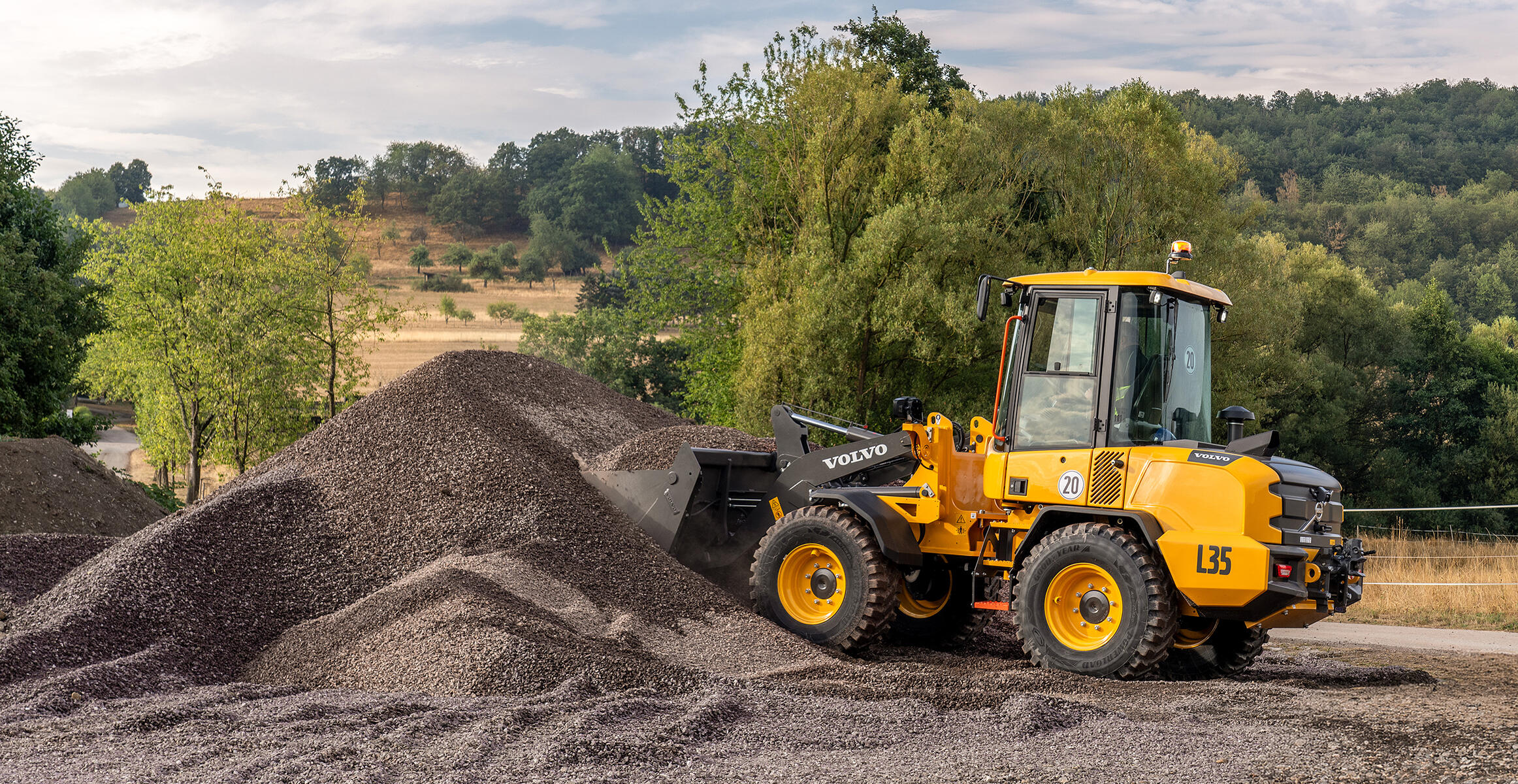 Volvo L35 Compact Wheel Loader working beside an aggregate pile on rough terrain.
