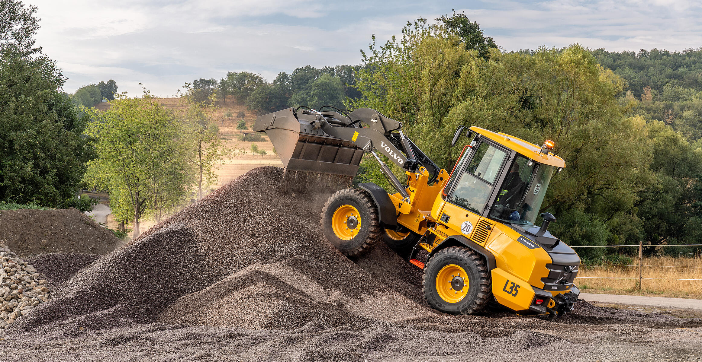 Volvo L35 Compact Wheel Loader driving over an aggregate pile on uneven terrain.