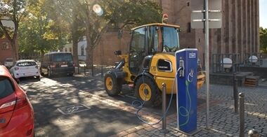 A Volvo L20 Electric Compact Wheel Loader plugged into a charger in a residential environment