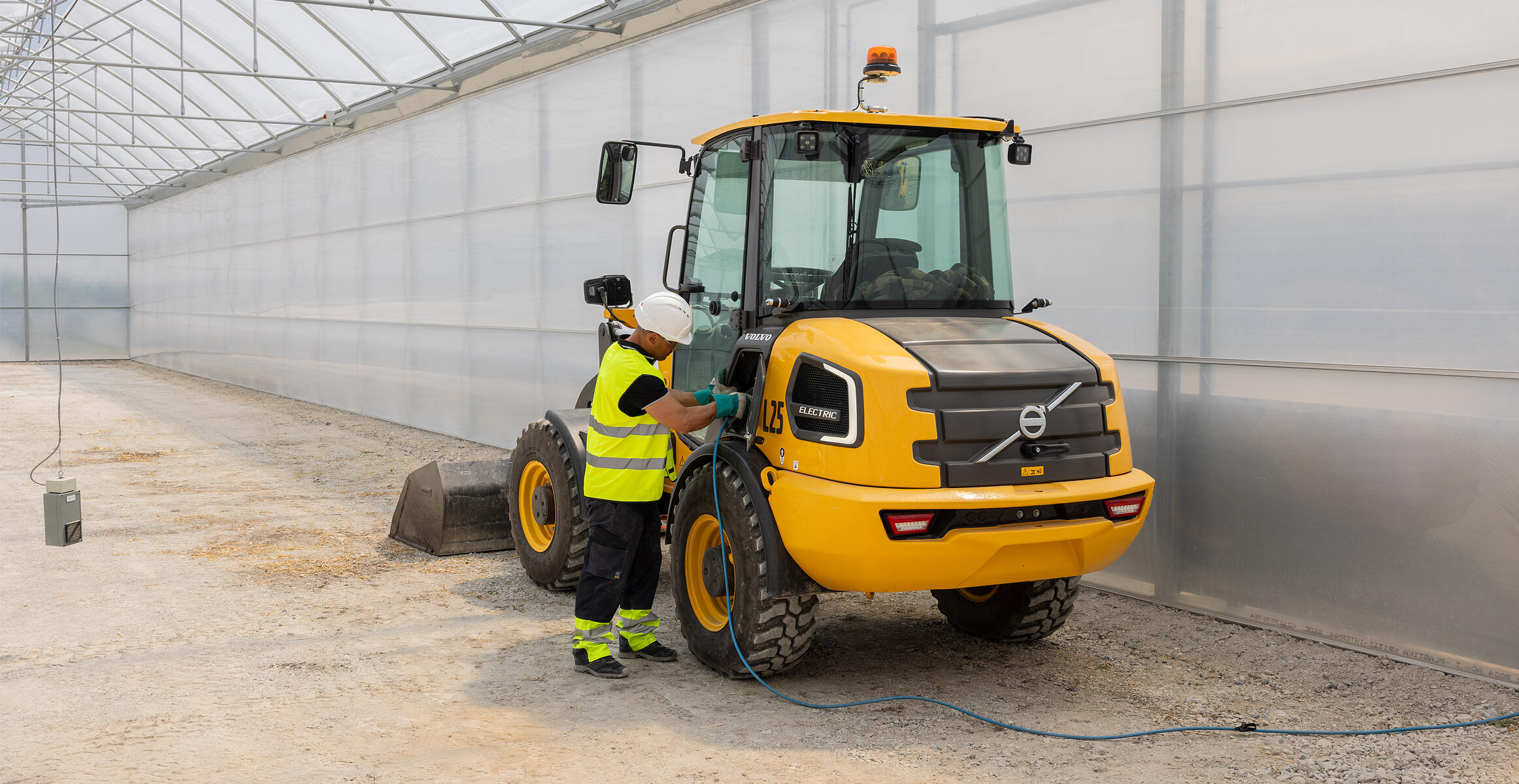 Elektryczna kompaktowa ładowarka kołowa Volvo L25 Electric podłączona do ładowarki w szklarni
