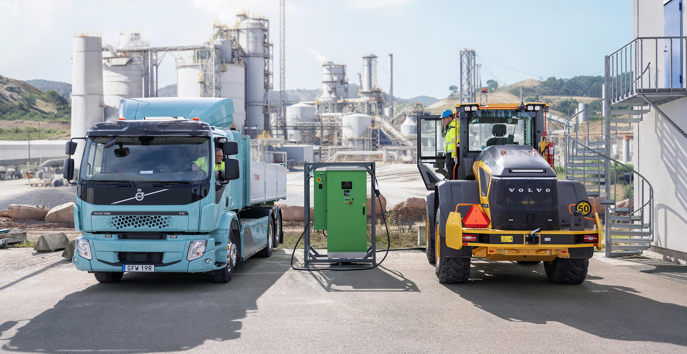 L90 electric wheel loader just arriving at the charging station with a Volvo electric truck