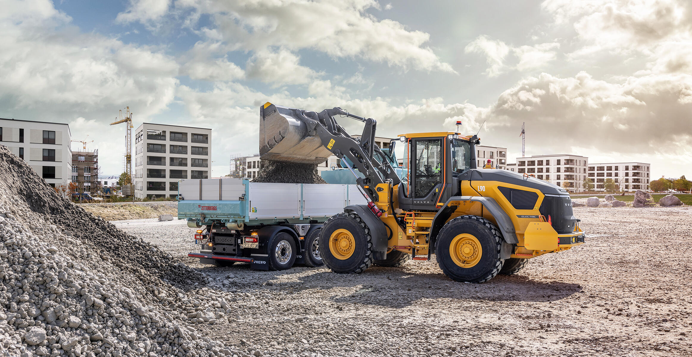 A L90 electric wheel loader emptying  bucket into a Volvo Truck