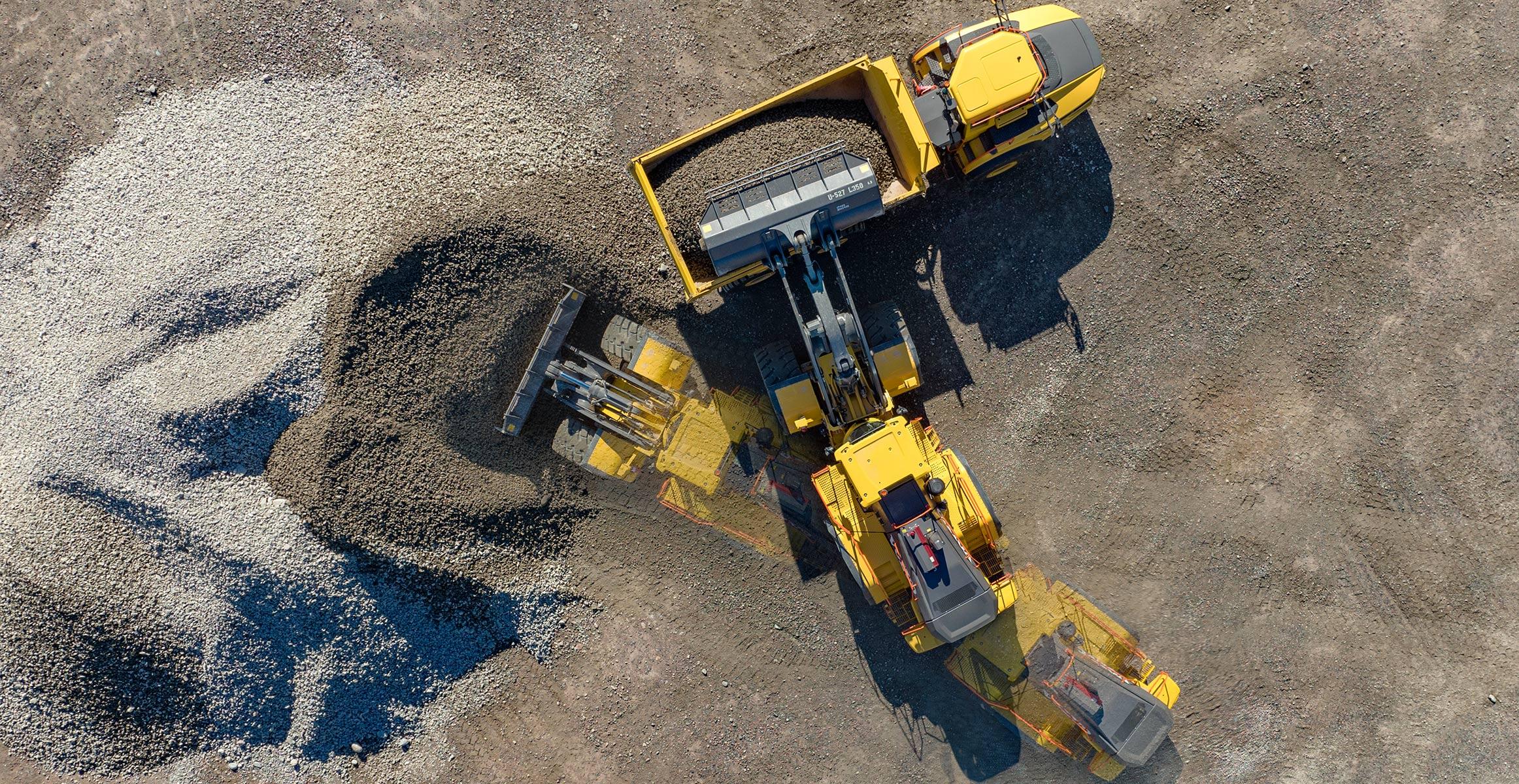 Drone  view of a L350H wheel loader fullfilling with gravels an articulated hauler.