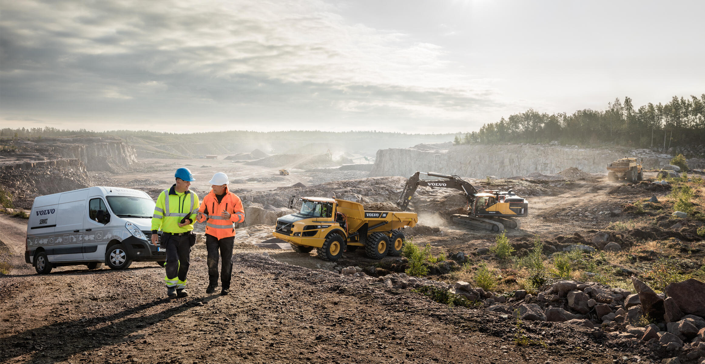 Volvo Construction Equipment operating at quarry site with workers reviewing plans