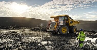 R100 rigid hauler arriving at a mining site, with two mine site managers giving arm signals to guide the truck driver for precise positioning and safe operation.
