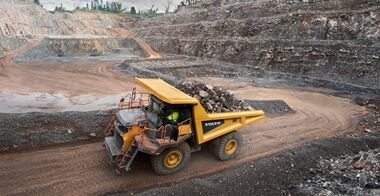 Side view of a Volvo R60 mining truck loaded with rock blocks.
