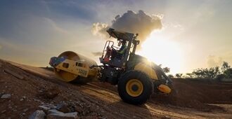 An SD120 roller climbing a steep slope to compact materials at the end of the day.