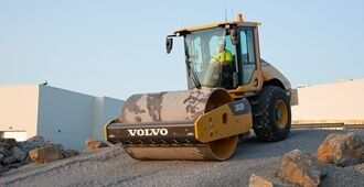 A Volvo SD125B soil compactor moving down a slope and compacting soils