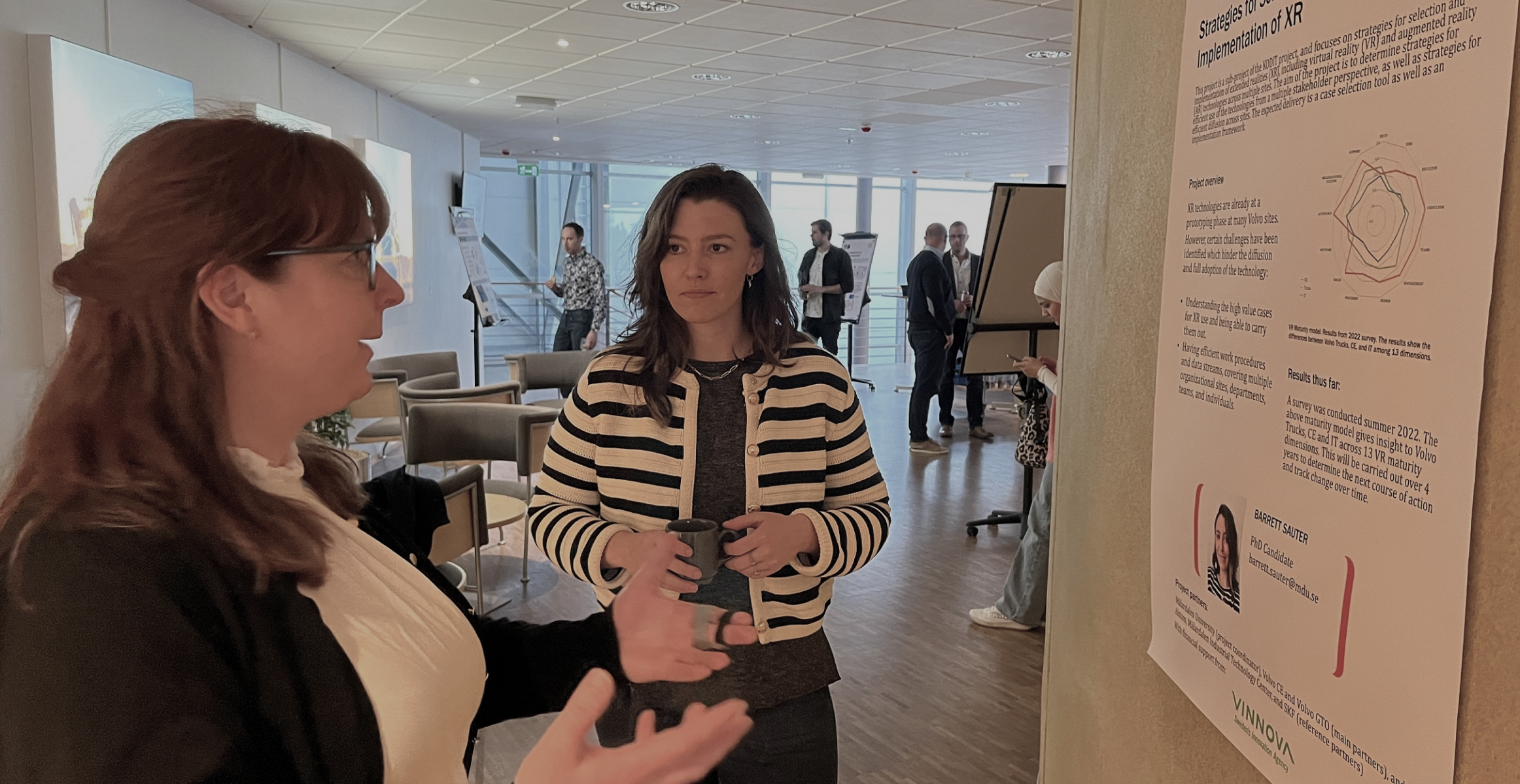 Two women discussing in front of a board of information