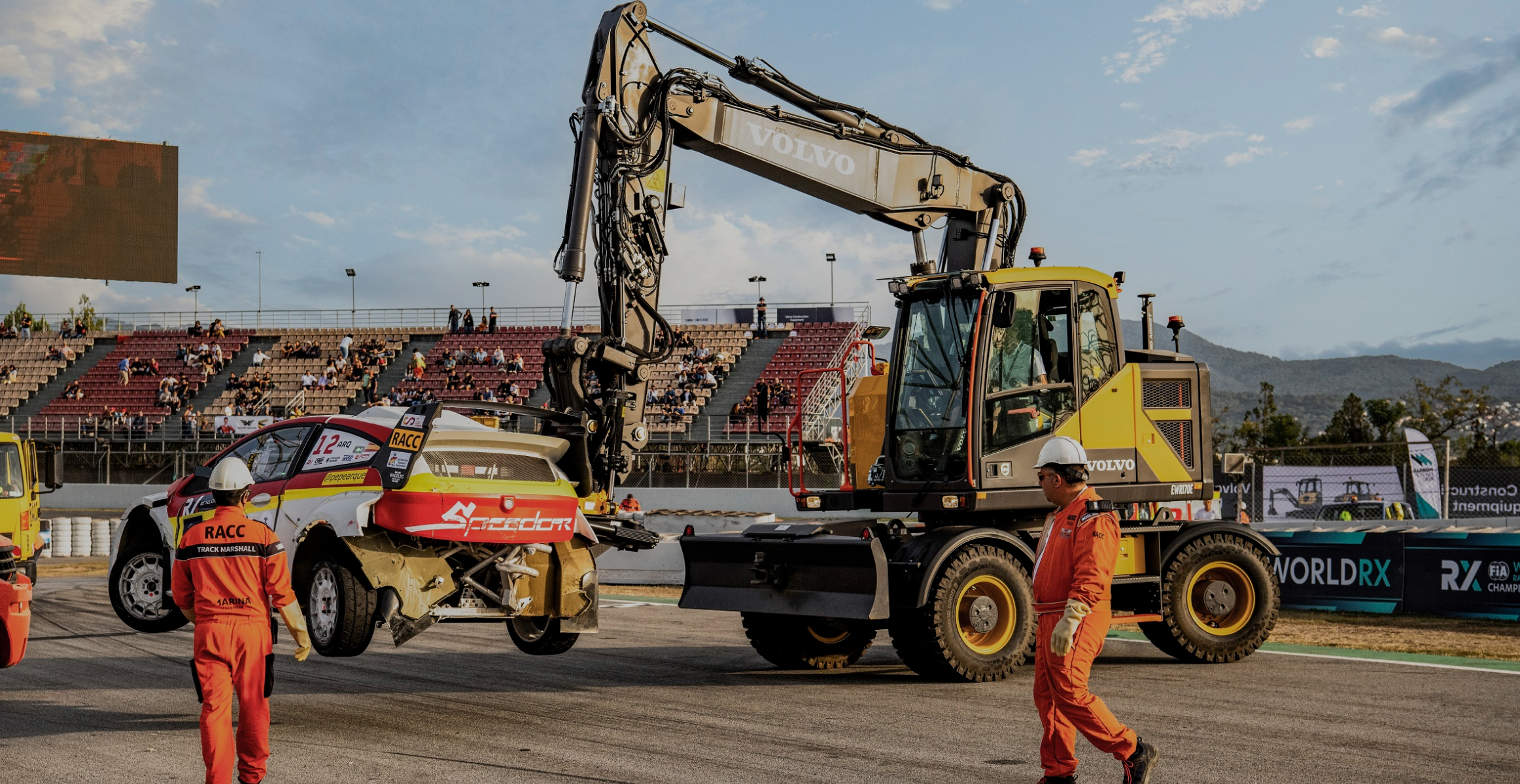 Electric excavator lifting car on race track 