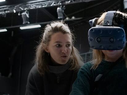 Child with VR glasses guided by woman