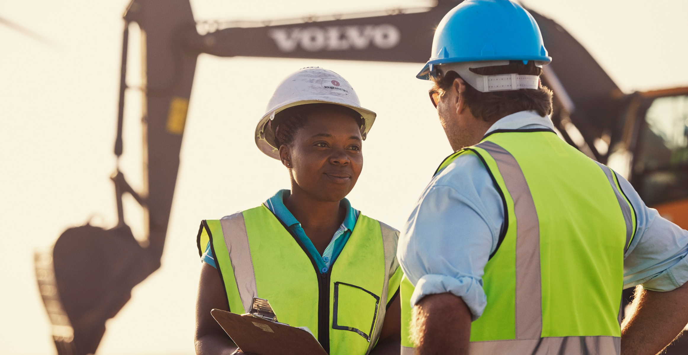 Man and woman talking with excavator in the background