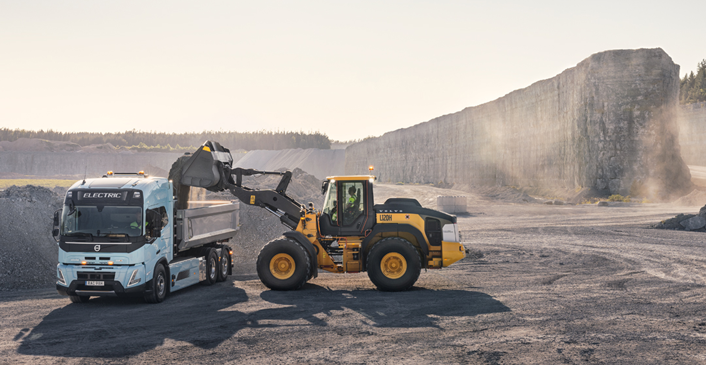 Volvo machine driving in sunset at wind park