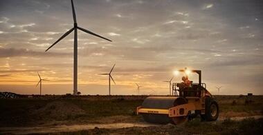 Volvo machine driving in sunset at wind park