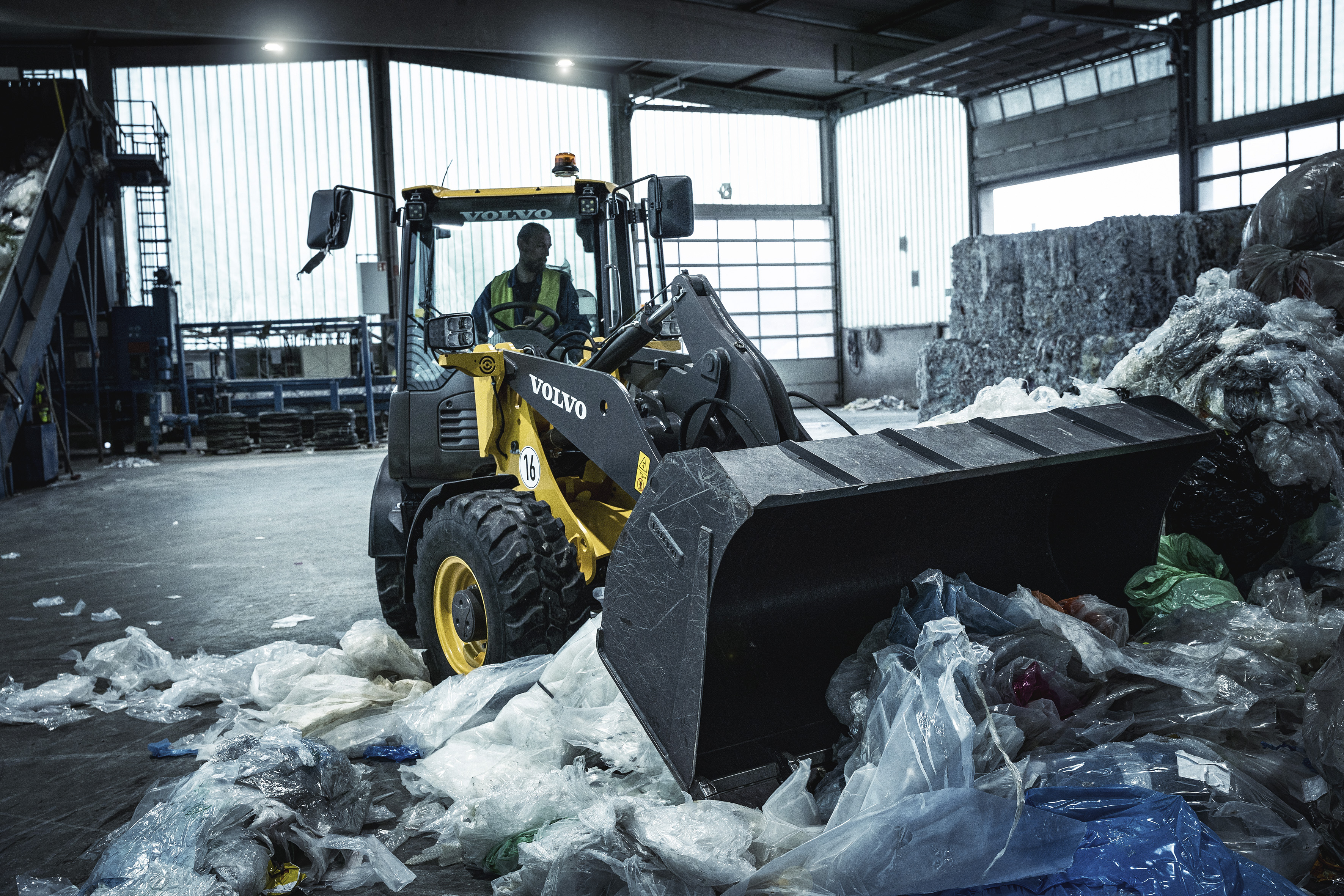an operator using a Volvo machine to remove recycling