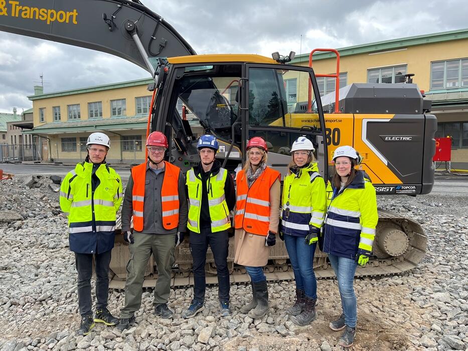 group of people in front of a Volvo electric truck at a construction worksite