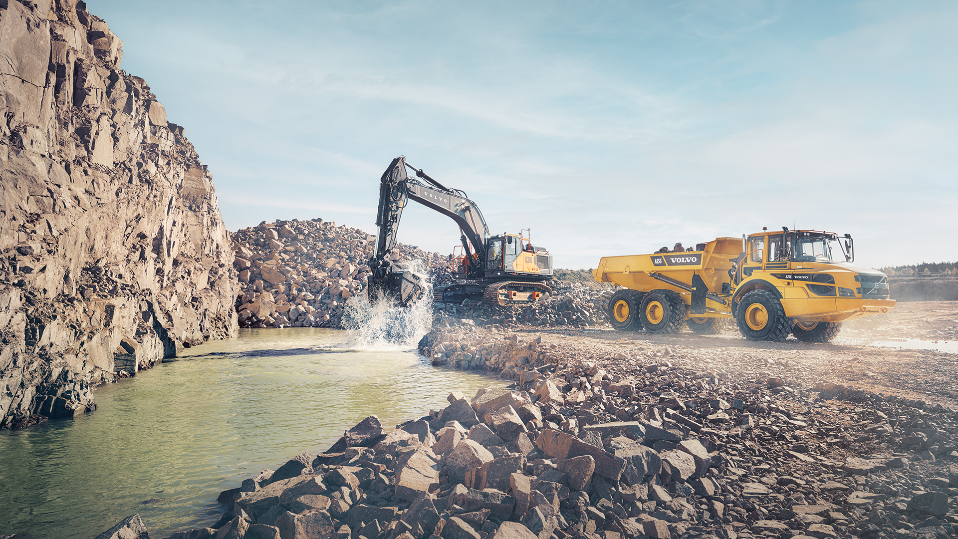 A Volvo machine by a pool of water and rocks at a worksite