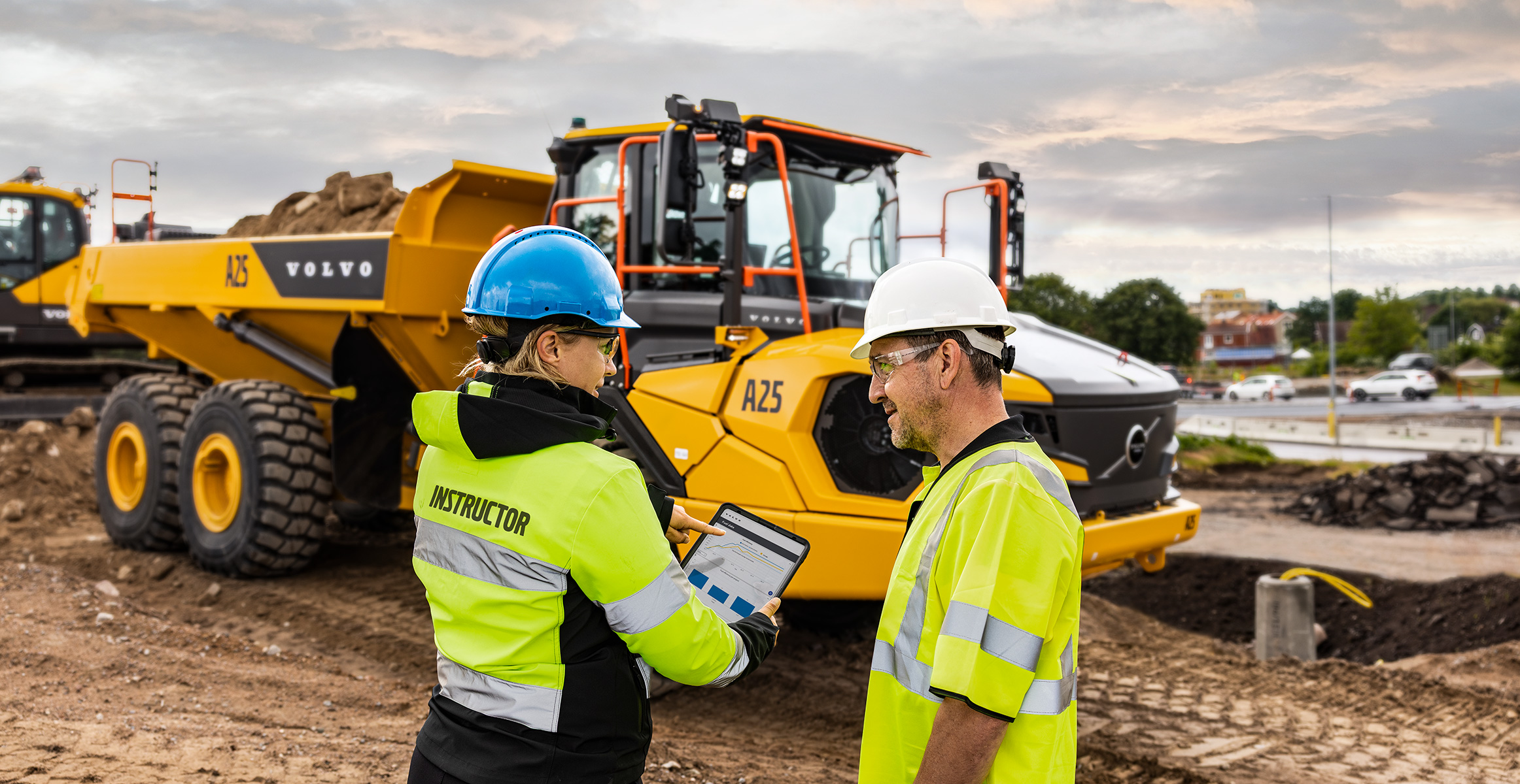 En instruktör visar en ramstyrd Volvodumper för en förare.