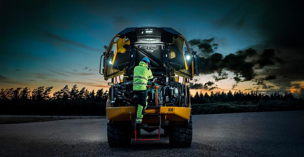 Construction equipment operator servicing a Volvo articulated hauler.