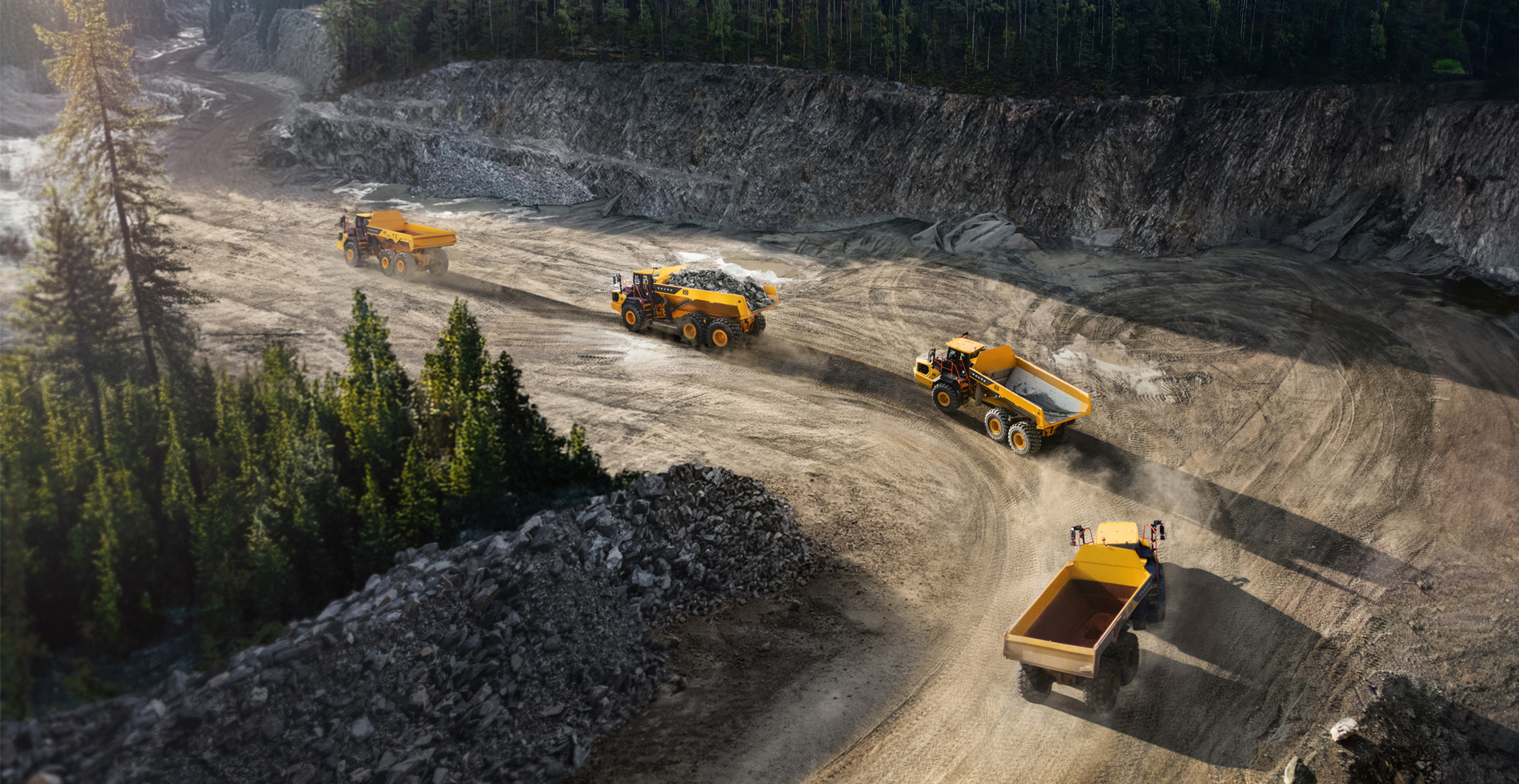 Volvo articulated hauler trucks rolling in line in a harsh environment.