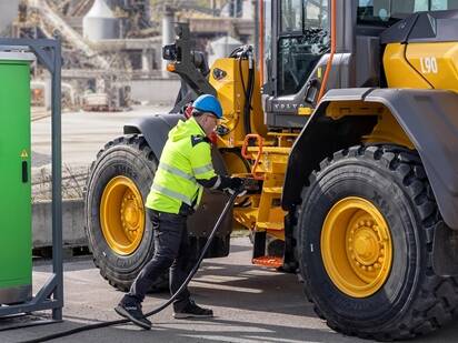 Charging mid-size excavator with a power unit