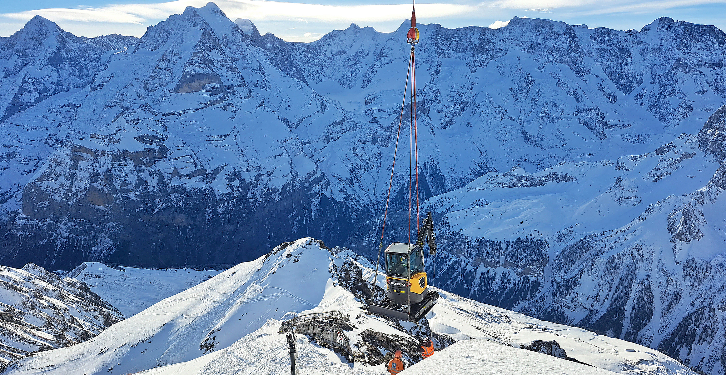 Electric excavator being air-lifted to perform recreation work on mount Schilthorn in the Swiss Alps.