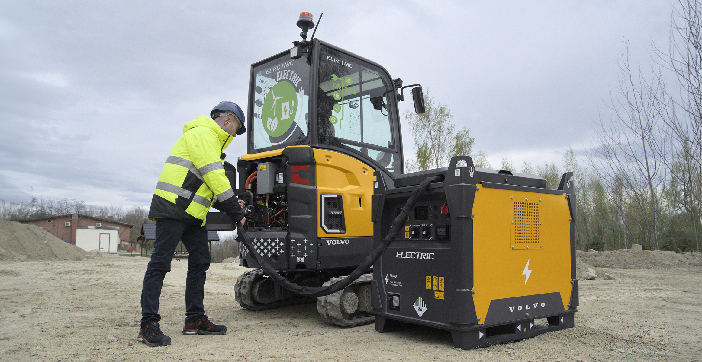 Operator charging compact electric construction machine with power unit.