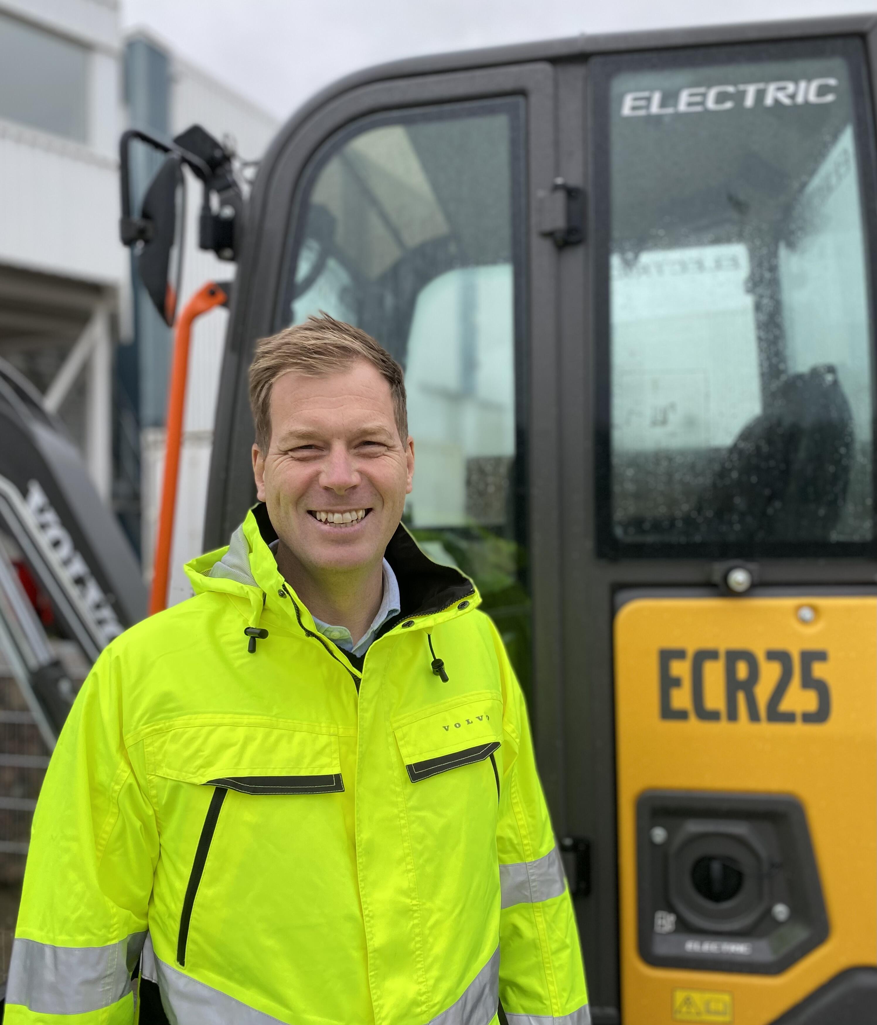 man smiling and standing in front of Volvo ECR25