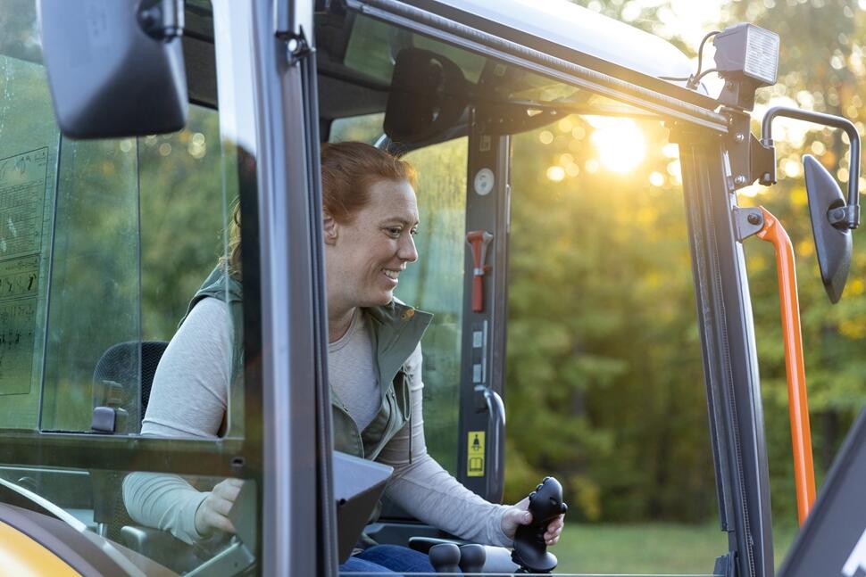 a woman operating a Volvo machine in a forest