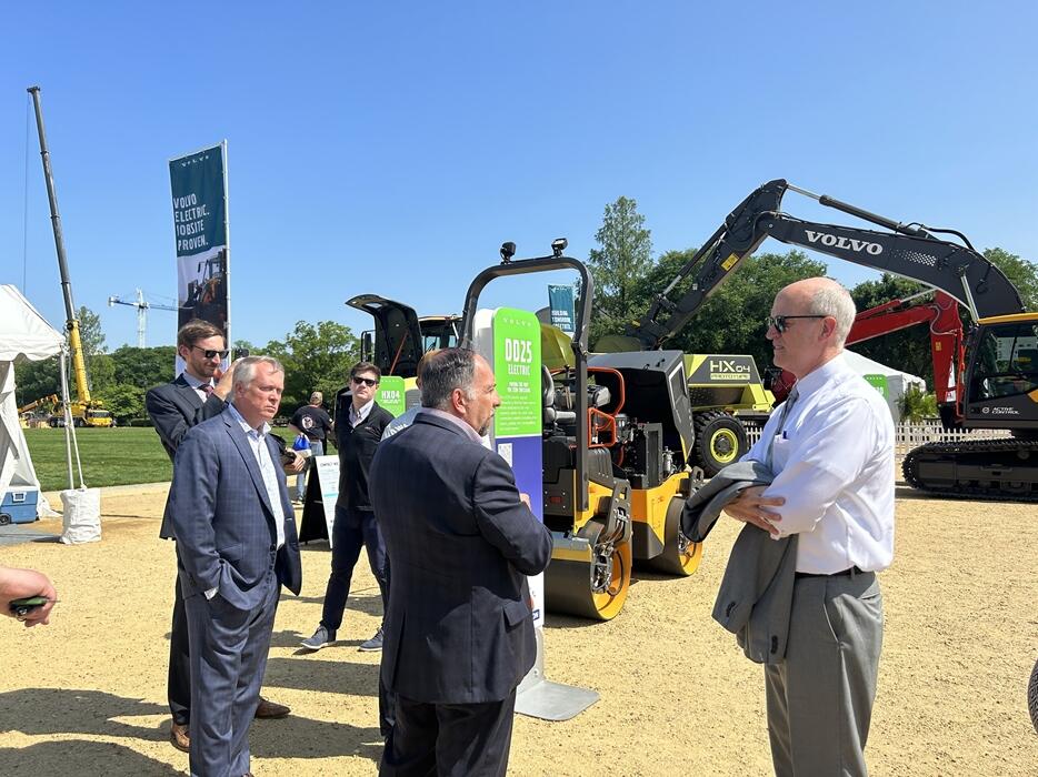 a group of men chatting in front of a volvo electric