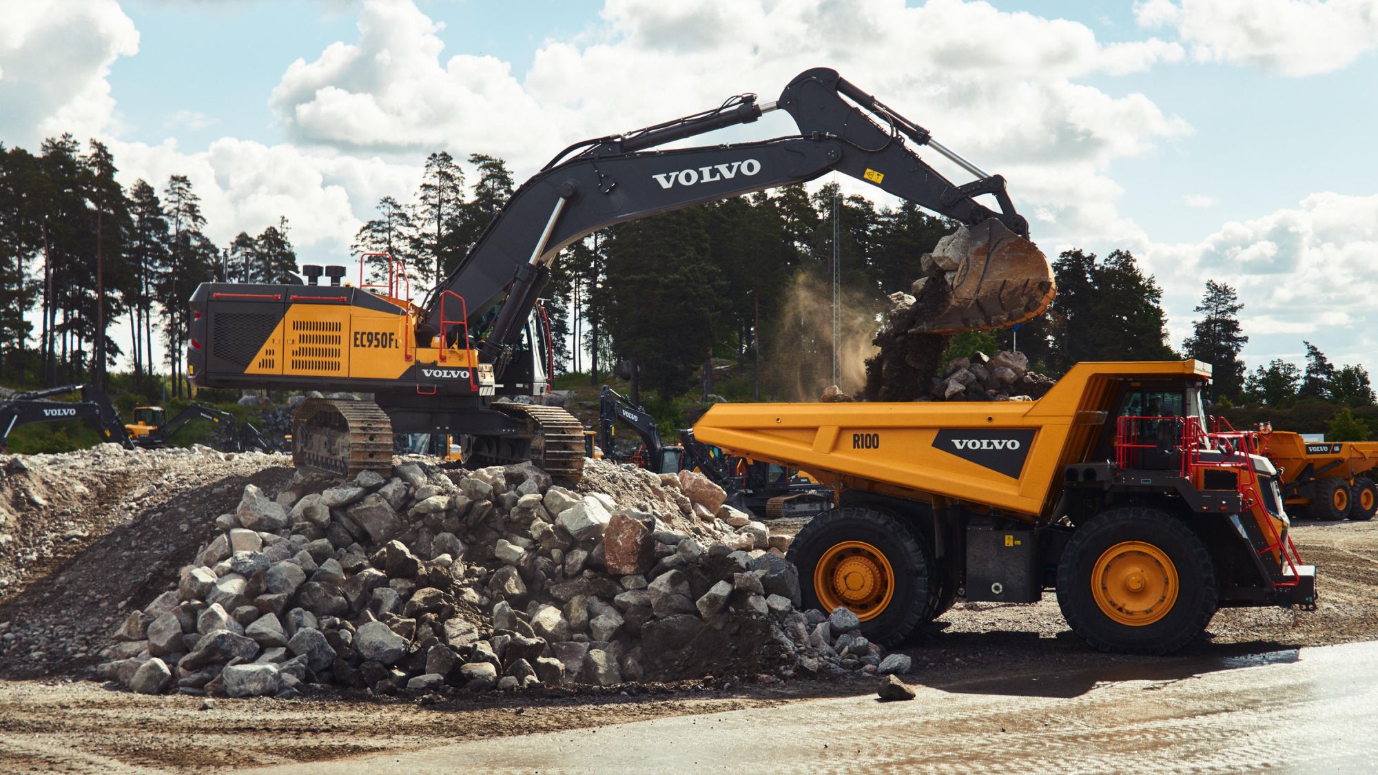 escavadeira carregando caminhão rígido com pedras