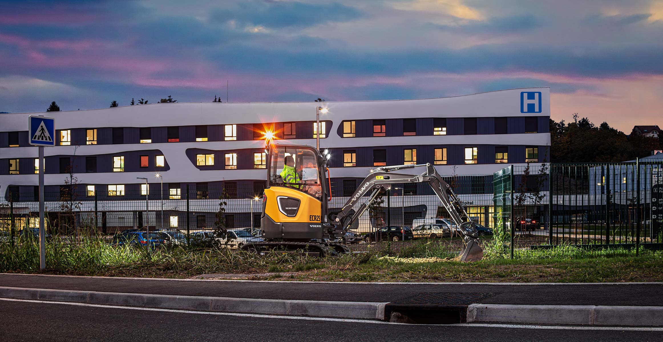 Volvo ECR25 electric excavator working in front of a hospital