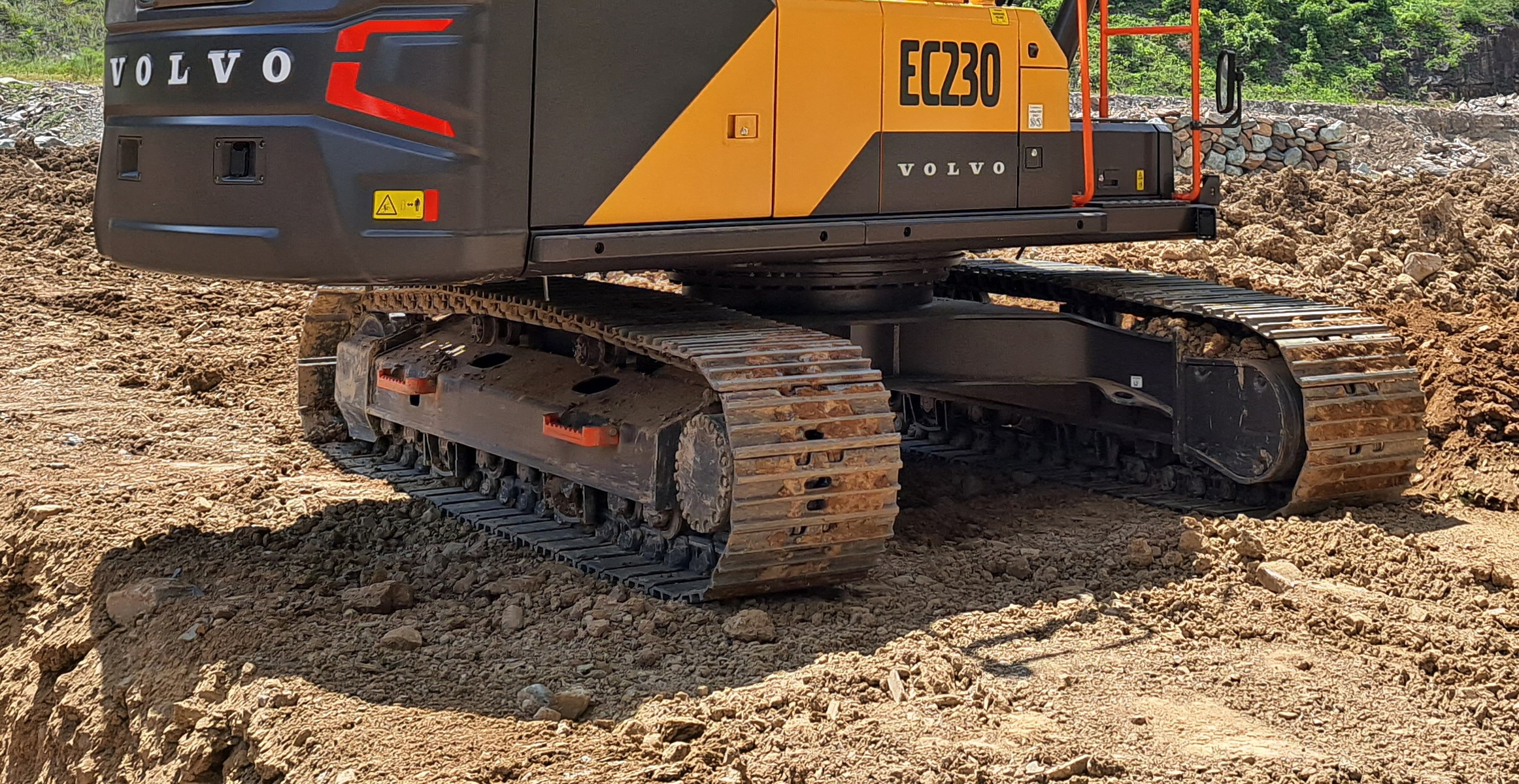 Close-up of a Volvo EC230 crawler excavator undercarriage.