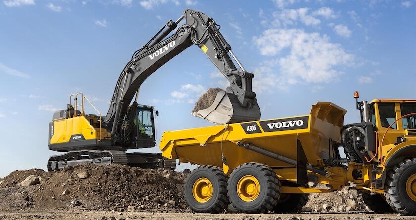 A Volvo EC320E crawler excavator loading a Volvo A30G articulated dump truck.